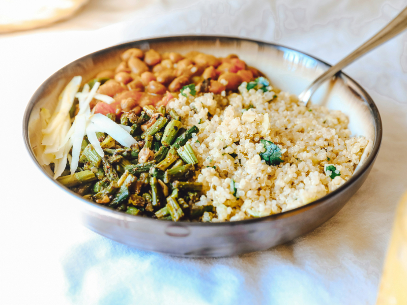 A bowl of cooked quinoa with fresh vegetables, a nutritious source of complex carbohydrates and plant-based protein.